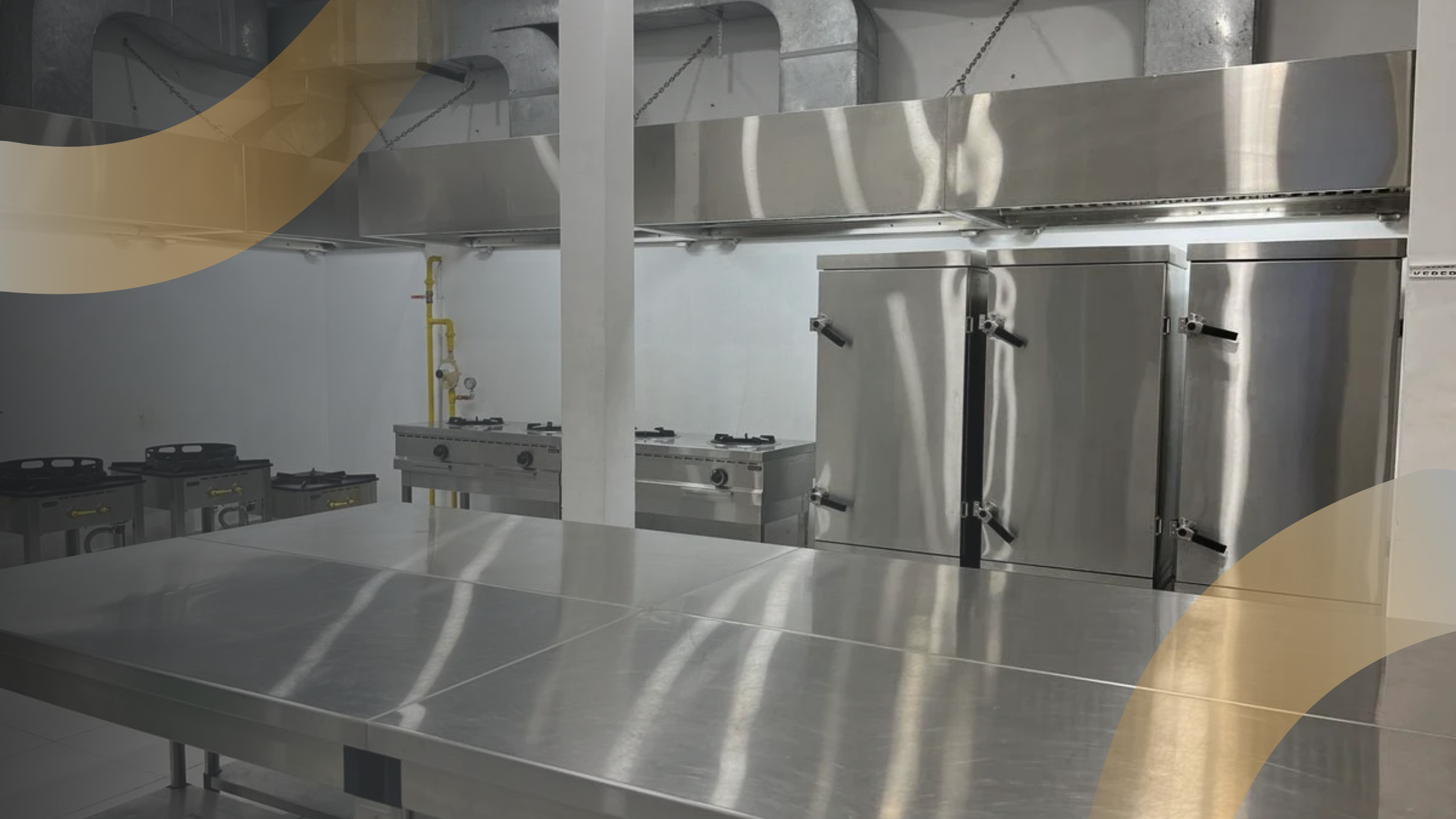 Dapur industri lengkap dengan peralatan stainless steel, kompor besar, dan permukaan kerja bersih serta rapi.
